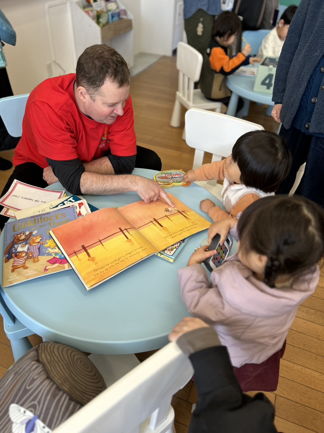 ISNの先生が子どもたちに英語の絵本を読み聞かせている様子