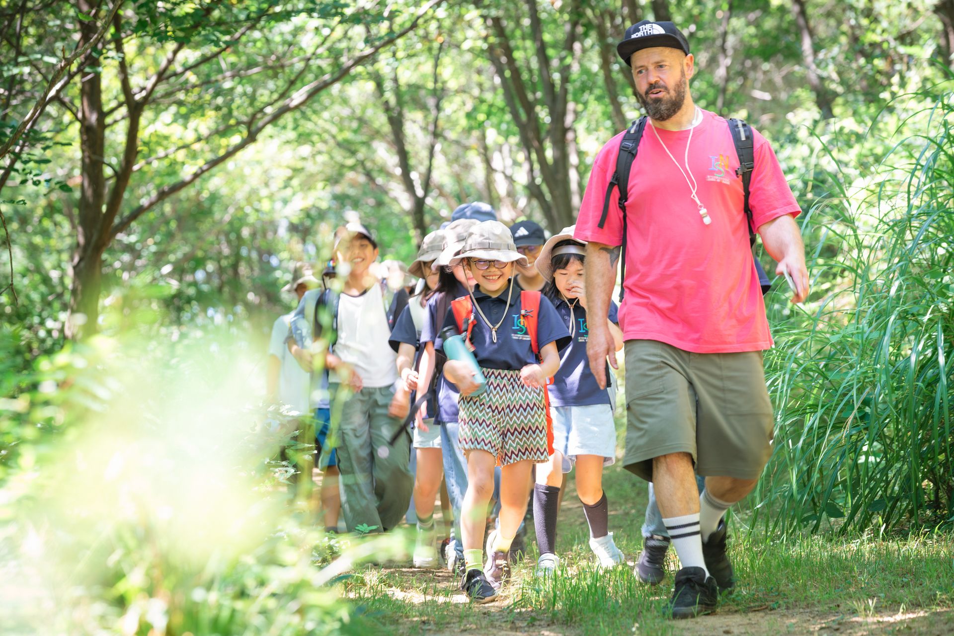 Gojo Campus Elementary School pupils walking a woodland trail with their teacher on a field trip